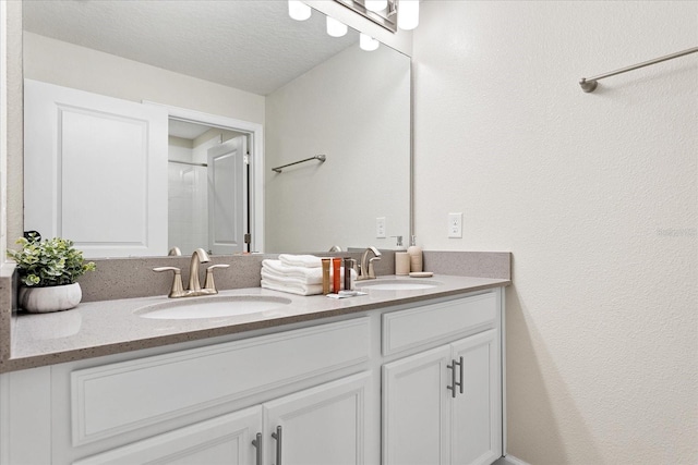 bathroom featuring walk in shower, vanity, and a textured ceiling