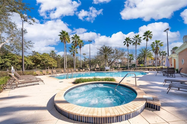 pool with a community hot tub, a patio, and fence