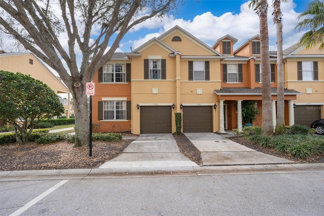 townhome / multi-family property with driveway, a garage, and stucco siding