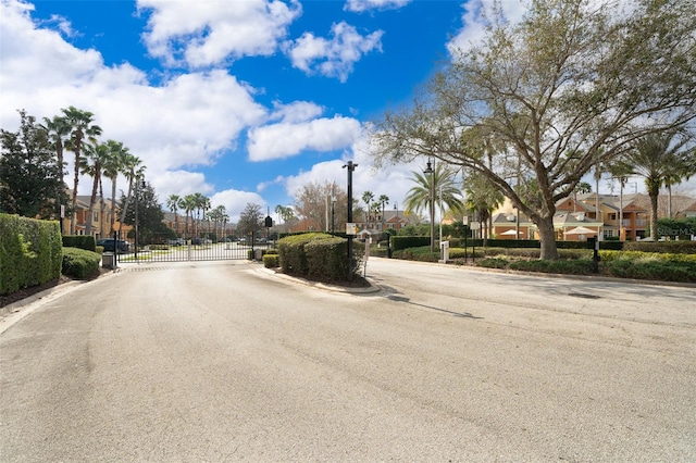 view of road with street lighting, a gate, a gated entry, a residential view, and curbs