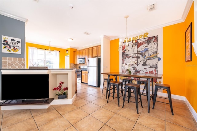 kitchen featuring stainless steel appliances, hanging light fixtures, visible vents, and crown molding