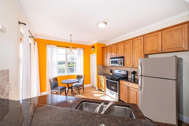 kitchen with dark countertops, hanging light fixtures, backsplash, appliances with stainless steel finishes, and a sink