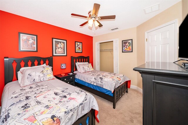 bedroom with a closet, visible vents, light carpet, and baseboards