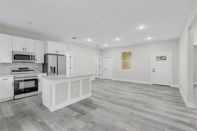 kitchen with white cabinetry, stainless steel appliances, a center island, and light hardwood / wood-style flooring