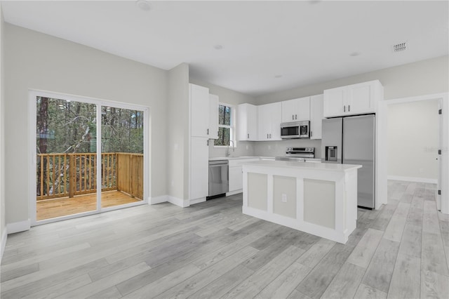 kitchen featuring white cabinetry, a kitchen island, light hardwood / wood-style floors, and appliances with stainless steel finishes