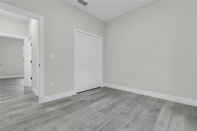 unfurnished bedroom featuring light wood-type flooring and a closet