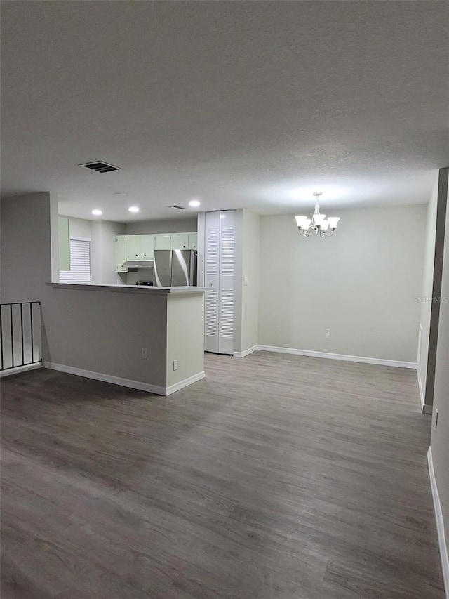 unfurnished living room featuring hardwood / wood-style flooring, a chandelier, and a textured ceiling