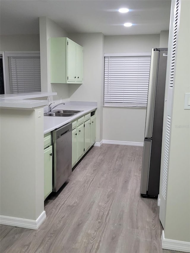 kitchen featuring appliances with stainless steel finishes, sink, green cabinets, and light hardwood / wood-style floors