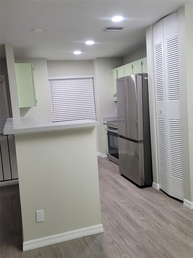 kitchen with stainless steel appliances, white cabinetry, light hardwood / wood-style floors, and kitchen peninsula