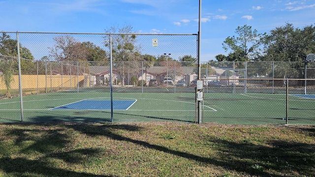 view of tennis court featuring a lawn