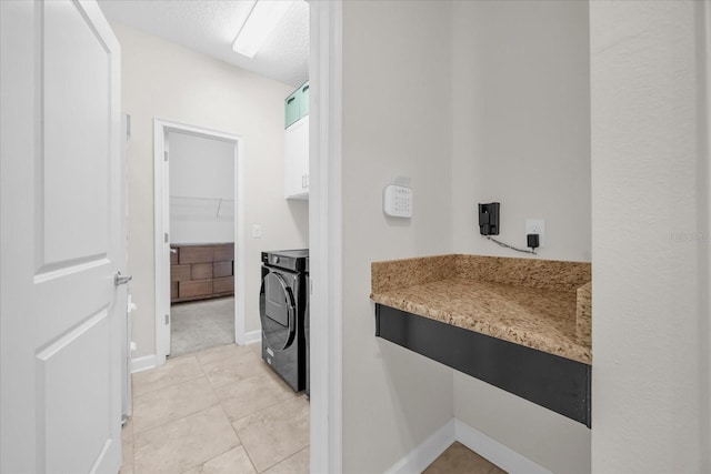 washroom with light tile patterned floors, cabinets, a textured ceiling, and washer and dryer