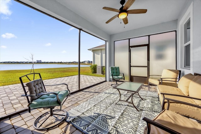 sunroom with ceiling fan and a water view