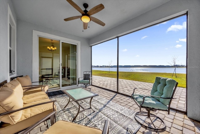 sunroom / solarium featuring ceiling fan with notable chandelier and a water view