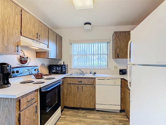 kitchen with light wood-type flooring, sink, and white appliances