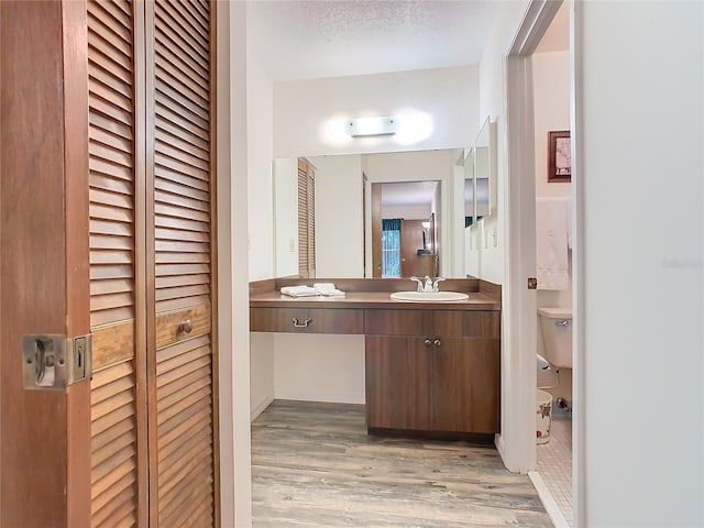 bathroom with hardwood / wood-style flooring, a textured ceiling, toilet, and vanity