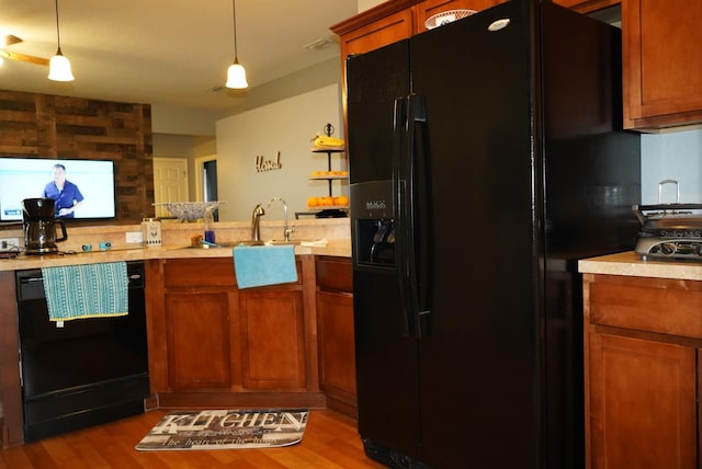 kitchen featuring light hardwood / wood-style floors, pendant lighting, and black appliances