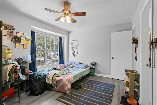 bedroom with ceiling fan, dark hardwood / wood-style floors, and a textured ceiling