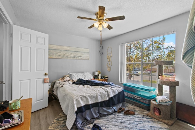 bedroom with hardwood / wood-style floors, a textured ceiling, and ceiling fan