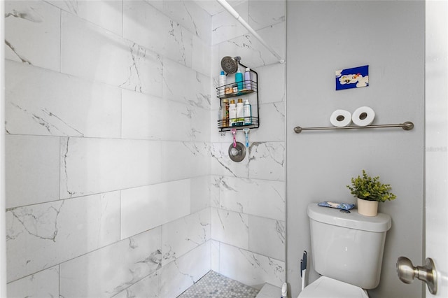 bathroom featuring tiled shower and toilet