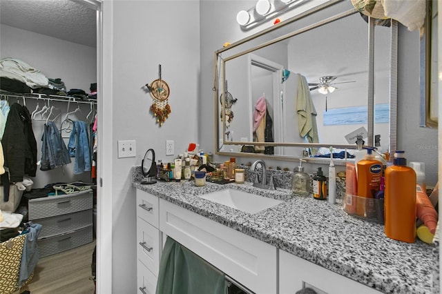 bathroom featuring wood-type flooring, a textured ceiling, ceiling fan, and vanity