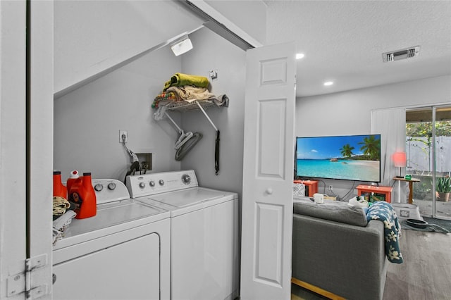 washroom with hardwood / wood-style flooring, a textured ceiling, and washer and dryer