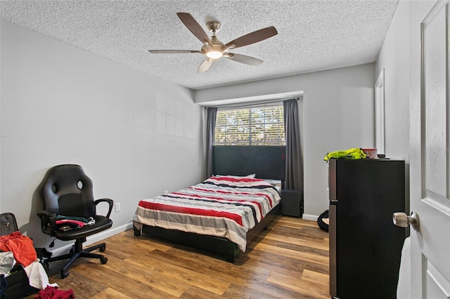 bedroom featuring ceiling fan, hardwood / wood-style floors, and a textured ceiling