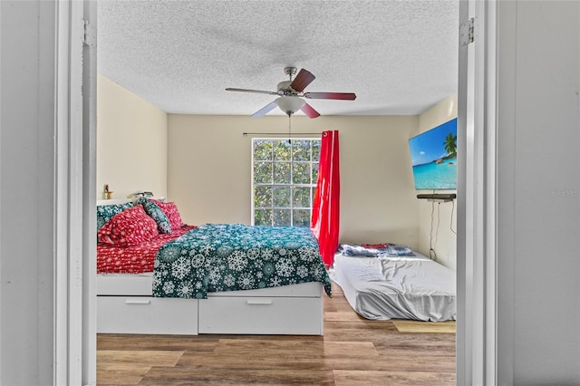 bedroom with a textured ceiling, light hardwood / wood-style flooring, and ceiling fan