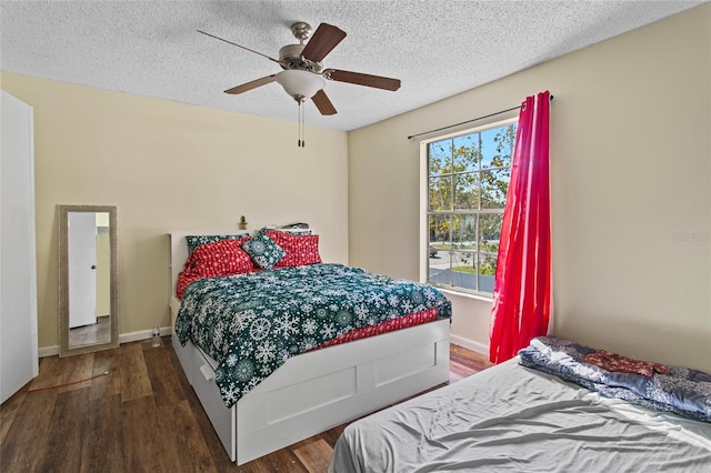 bedroom with multiple windows, a textured ceiling, dark wood-type flooring, and ceiling fan