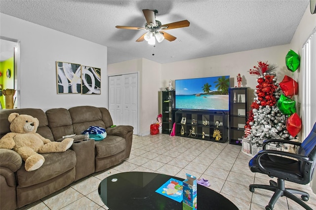 living room with ceiling fan, a textured ceiling, and light tile patterned floors