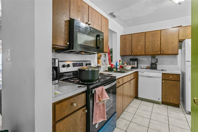 kitchen featuring sink, light tile patterned flooring, and white appliances