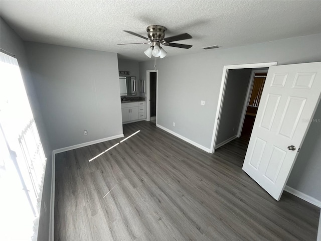 unfurnished living room with ceiling fan, a textured ceiling, and dark hardwood / wood-style floors