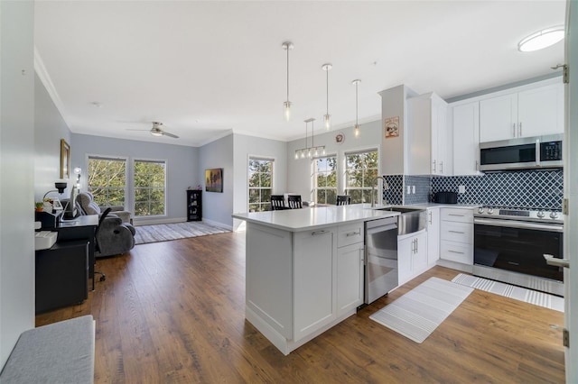 kitchen featuring backsplash, pendant lighting, kitchen peninsula, stainless steel appliances, and white cabinets