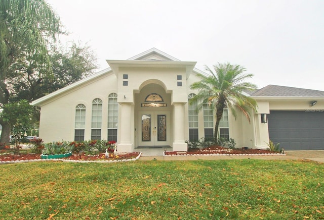 mediterranean / spanish house with a garage, a front lawn, and french doors