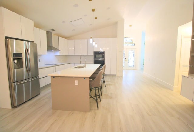 kitchen with pendant lighting, white cabinets, wall chimney exhaust hood, stainless steel appliances, and sink