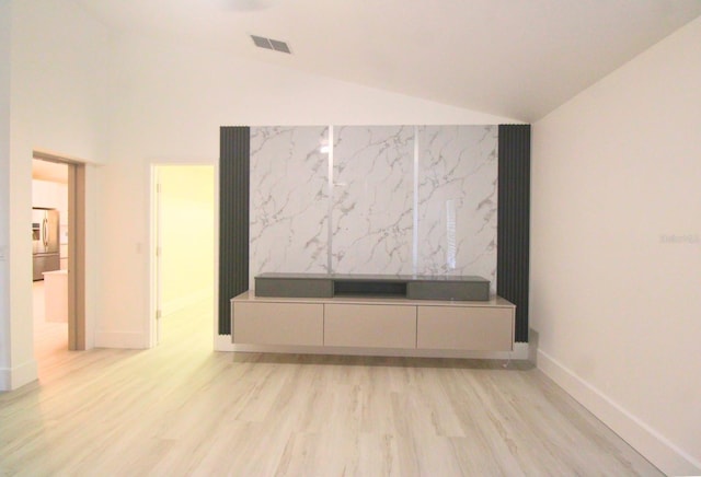 unfurnished living room featuring high vaulted ceiling and light wood-type flooring