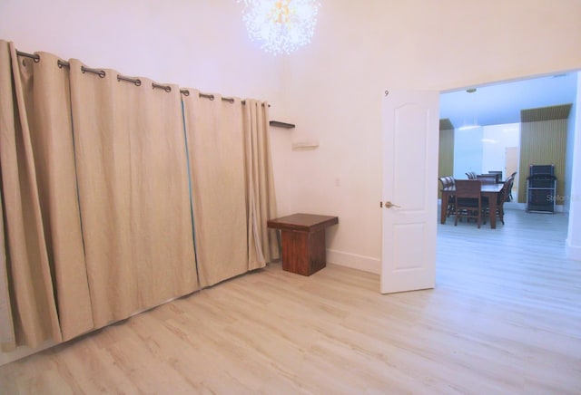 spare room with light wood-type flooring, baseboards, and a chandelier