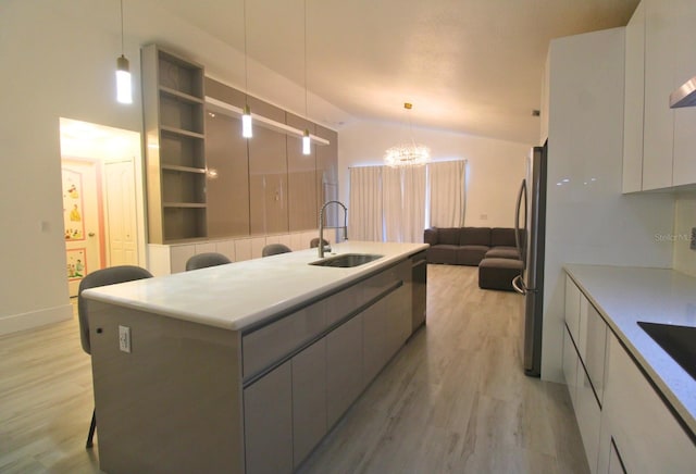 kitchen featuring white cabinets, a kitchen island, light hardwood / wood-style floors, sink, and hanging light fixtures