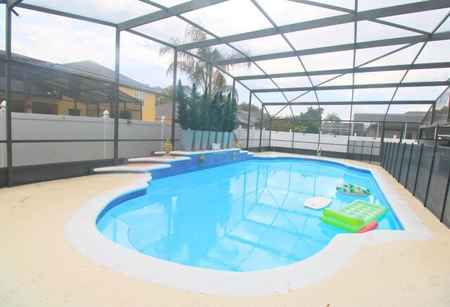 view of swimming pool with a fenced in pool, glass enclosure, a patio, and a fenced backyard