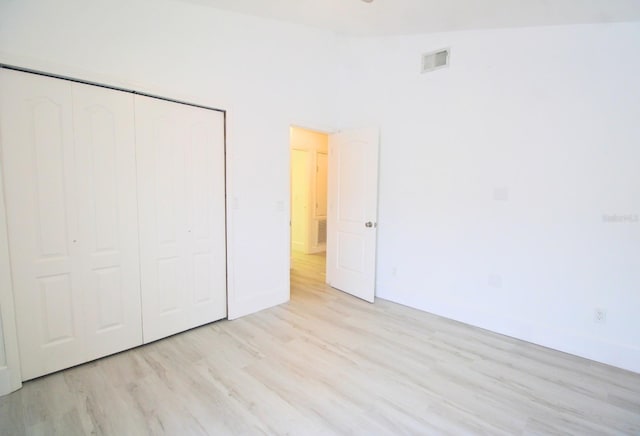 unfurnished bedroom featuring light wood-type flooring, a closet, and visible vents