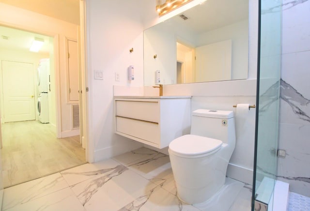 full bath with washer / dryer, a marble finish shower, toilet, marble finish floor, and vanity