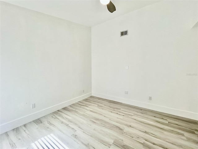 spare room with light wood finished floors, a ceiling fan, visible vents, and baseboards