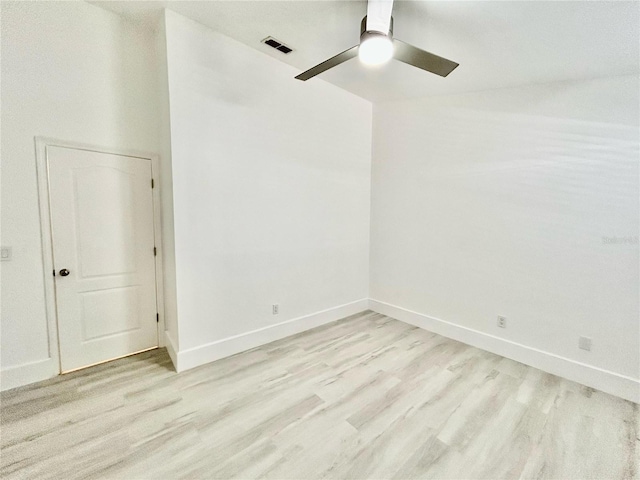 spare room featuring light wood finished floors, baseboards, visible vents, and a ceiling fan