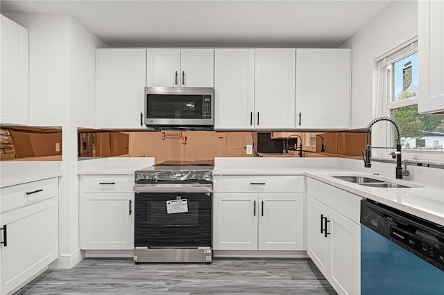 kitchen featuring light wood-type flooring, appliances with stainless steel finishes, white cabinetry, and sink