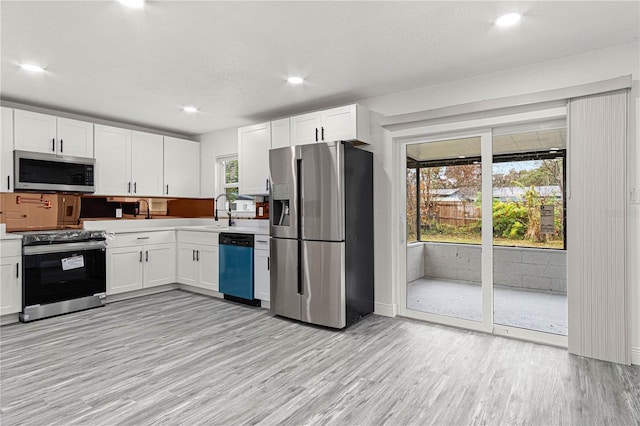 kitchen with light wood-type flooring, stainless steel appliances, white cabinets, and sink