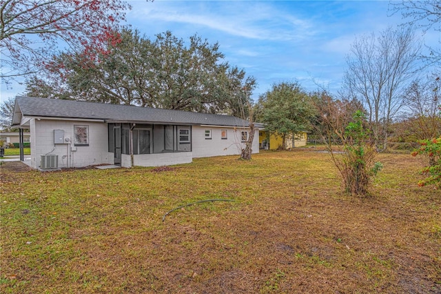 back of house with central AC unit, a yard, and a sunroom