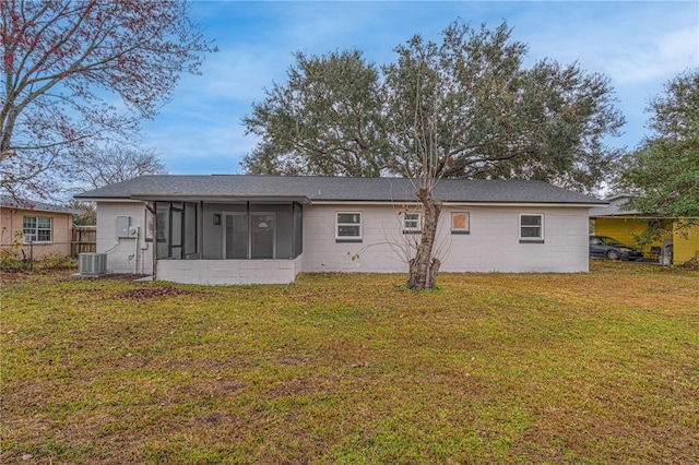 rear view of house featuring central AC unit, a sunroom, and a yard