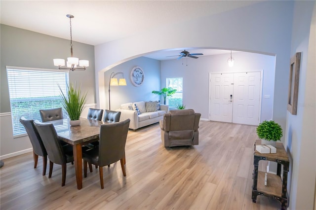 dining room with light wood-type flooring, lofted ceiling, and ceiling fan with notable chandelier