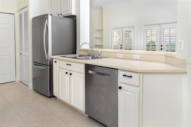 kitchen with kitchen peninsula, appliances with stainless steel finishes, sink, white cabinetry, and light tile patterned flooring