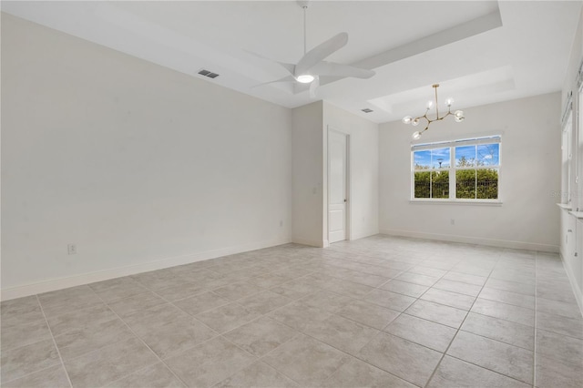 unfurnished room featuring ceiling fan with notable chandelier, light tile patterned floors, and a raised ceiling