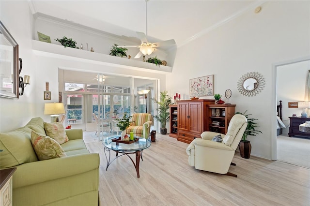 living room featuring ceiling fan, ornamental molding, and a towering ceiling